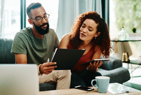 Couple looking at a computer tablet and reviewing papers.